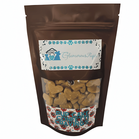 8oz bag of Pup Cake Confetti Cravings Dog Treats by Glamorous Pups, presented in a glossy brown resealable package with a transparent window showcasing heart-shaped, golden treats speckled with colorful confetti. The package features the Glamorous Pups logo and blue paw prints, emphasizing the festive and gourmet appeal of these all-natural dog treats. Ideal for pet owners looking for fun, high-quality snacks that are made in the USA.