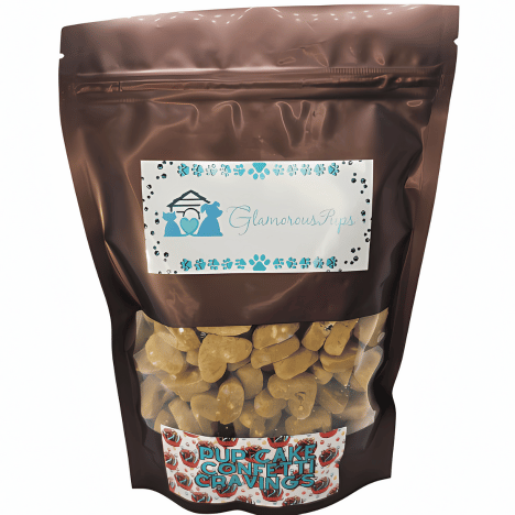 1lb bag of Pup Cake Confetti Cravings Dog Treats by Glamorous Pups, displayed in a glossy brown resealable package with a clear viewing window revealing heart-shaped, golden treats inside. The label features the Glamorous Pups logo and blue paw prints, with the product name 'Pup Cake Confetti Cravings' prominently displayed. This packaging is designed to attract pet owners seeking festive, gourmet, all-natural dog treats made in the USA.