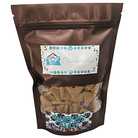 1lb resealable bag of Blueberry Pupcake Party by Glamorous Pups, featuring a sleek, glossy brown design with a clear viewing window that showcases the party hat-shaped, blueberry-infused treats inside. The bag's label is adorned with the Glamorous Pups logo and blue paw prints, underlining the product's high-quality, all-natural ingredients. This packaging is specifically designed to appeal to pet owners looking for nutritious, made-in-the-USA dog treats.