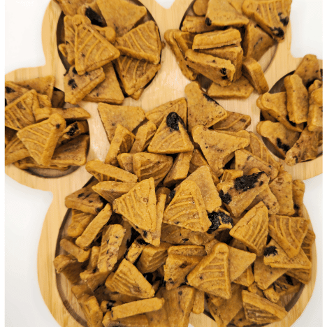 Close-up of Blueberry Pupcake Party treats by Glamorous Pups, artfully arranged on a wooden paw print-shaped serving board. Each treat is shaped like a small pancake and dotted with real blueberry pieces, highlighting the natural and delicious ingredients. This visually appealing setup underscores the quality and uniqueness of these made-in-the-USA, all-natural dog treats, perfect for health-conscious pet owners.