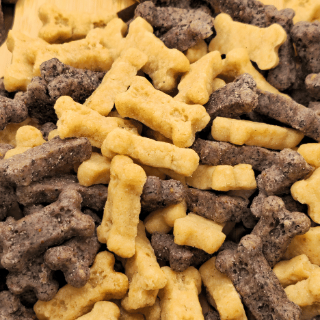 Zoomed-in view of Gentle Berry Bites by Glamorous Pups, showcasing a mix of high-quality, all-natural dog treats on a wooden paw print-shaped board. The treats are intricately shaped like bones in shades of light beige and dark brown, emphasizing their wholesome, berry-infused ingredients ideal for dog training and health-conscious pet owners.