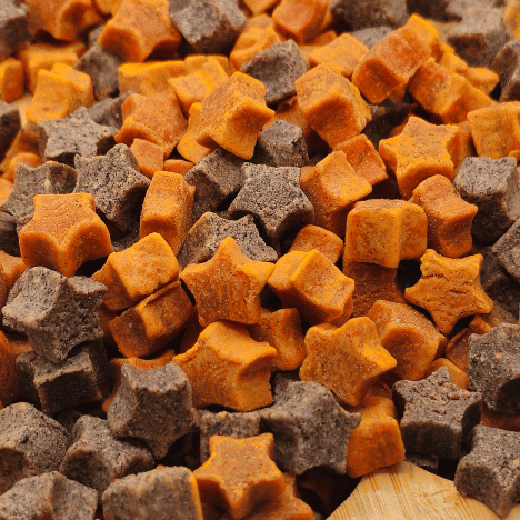 Close-up view of Cosmic Pupkin Berry Dog Treats by Glamorous Pups, showcasing the star and cube-shaped treats in vibrant orange and deep brown colors. These gourmet dog treats combine flavors of pumpkin and berry, making them a nutritious choice for pet owners seeking USA-made, all-natural snacks for their dogs.