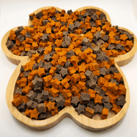 Top view of Cosmic Pupkin Berry Dog Treats by Glamorous Pups, arranged on a wooden paw-shaped board. These star and cube-shaped treats offer a mix of pumpkin and berry flavors, perfect for pets. Packed with nutritional benefits and crafted from all-natural ingredients, these treats are ideal for dog owners looking for premium, healthy snacks for their furry friends.