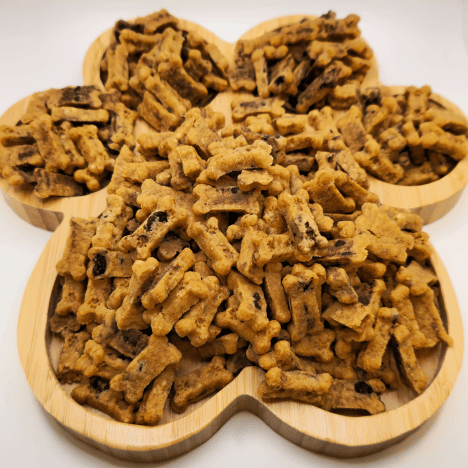 Plentiful display of Choco-Chip Pup Crunchers Dog Treats by Glamorous Pups, arranged on a wooden paw-shaped serving board. These visually appealing, nutritious dog treats are packed with wholesome ingredients and carob chips, making them an irresistible snack for pets.