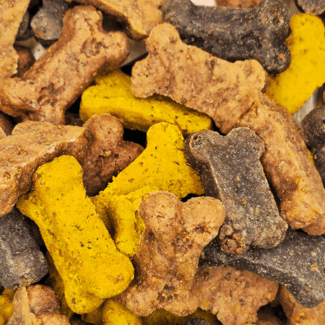 Close-up view of Feast of Beasts Pup-Pleaser Dog Treats by Glamorous Pups, featuring a mix of yellow, brown, and gray bone-shaped treats rich in natural flavors of beef, turkey, and chicken, ideal for dog owners searching for premium, flavorful, and healthy dog snacks.