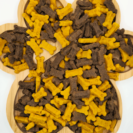 Overhead view of Bacon-Egg Pawfection Dog Treats by Glamorous Pups. These bone-shaped treats come in a vibrant mix of yellow and brown, representing the savory flavors of bacon and egg. Ideal for pet owners seeking nutritious and flavorful treats for their dogs.