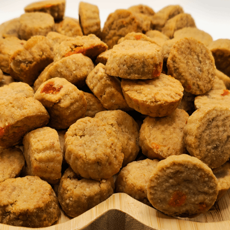 Detailed image of Tropical Pupaya Paradise Dog Treats by Glamorous Pups, heaped on a wooden, paw-shaped platter. Each treat features an enticing blend of pineapple and papaya, providing a rich, savory option for pet owners who prioritize healthful, flavorful snacks for their dogs.