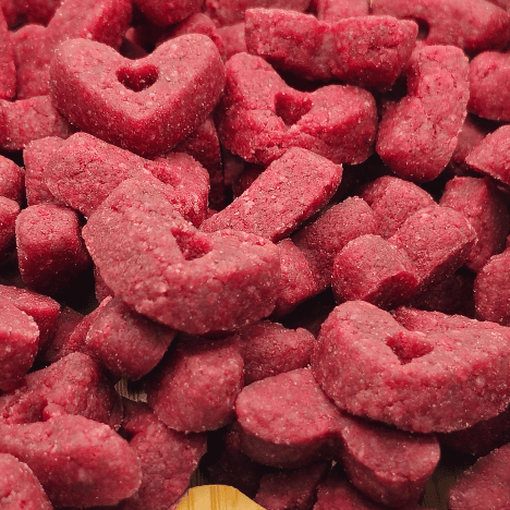 Close-up view of Velvet Love Whispers Dog Treats by Glamorous Pups, showcasing dense, heart-shaped treats with a rich, red hue, perfect for dog owners looking to pamper their pets with high-quality, delicious snacks.