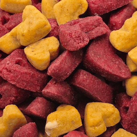 Close-up view of Pup's Love Kisses Dog Treats by Glamorous Pups, showcasing heart-shaped treats in vibrant cranberry and mustard yellow colors, ideal for rewarding your beloved dog with nutritious, delectable snacks.