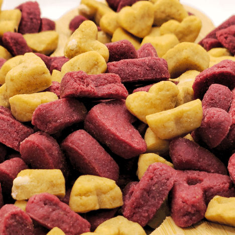 Close-up of Pup's Love Kisses Dog Treats by Glamorous Pups, showcasing heart-shaped treats in vibrant red and yellow colors, perfect for rewarding your beloved dog with delicious, healthy snacks.