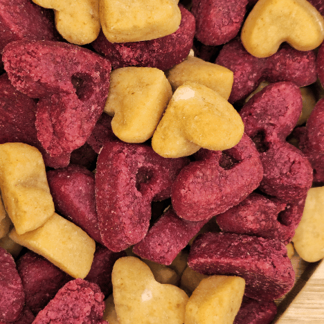 Zoomed-in view of Pup's Love Kisses Dog Treats by Glamorous Pups, featuring heart-shaped, dual-colored treats in deep cranberry and golden hues, designed to provide tasty, healthy options for your canine companion.