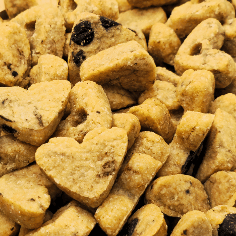 Close-up view of Peanut Butter Pup Dog Treats by Glamorous Pups featuring a mix of heart-shaped and bone-shaped biscuits with visible peanut pieces, perfect for pet owners looking for premium, handmade dog treats crafted in the USA by Glamorous Pups.