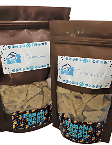 Packaging for Banana Bash Caps Dog Treats by Glamorous Pups, featuring two bag sizes. Each resealable bag has a clear window displaying unique cap-shaped treats. The vibrant blue and orange label includes the Glamorous Pups logo surrounded by blue paw prints, emphasizing the brand's commitment to all-natural, healthy dog snacks. The festive 'Banana Bash Caps' text enhances the appeal for pet owners seeking fun and nutritious treats for their dogs.