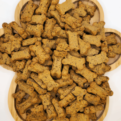 Array of Pupkin Patch Snacks Dog Treats by Glamorous Pups arranged on a bamboo serving board in heart and bone shapes, showcasing their natural, rough texture and wholesome ingredients, perfect for health-conscious dog owners.