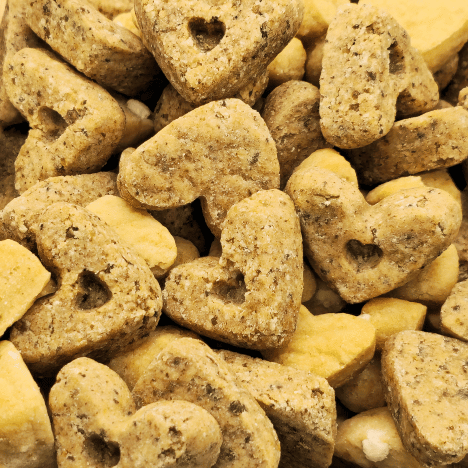 Detailed close-up of Sweet À La Mode Dog Treats by Glamorous Pups, showcasing a mix of heart-shaped treats in golden and speckled gray hues. These treats highlight their premium, all-natural ingredients, catering to pet owners seeking nutritious and gourmet snacks for their dogs. Crafted with care in the USA, these treats embody Glamorous Pups’ commitment to quality and creativity in pet nutrition.