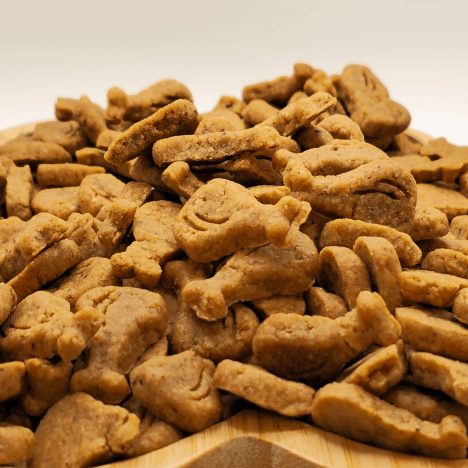 Close-up of a heaping pile of Drumstick & Waffle Poppers Dog Treats by Glamorous Pups, arranged on a wooden paw print-shaped serving board. These treats, crafted to resemble drumsticks and waffles, offer a detailed look at their unique shapes and rich, natural texture. Perfect for pet owners seeking creative, nutritious snacks for their dogs, these treats are made with all-natural ingredients and embody Glamorous Pups' commitment to quality and made-in-the-USA products.