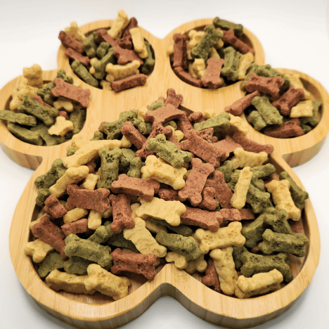 Zoomed-in image of Frostbite Fruity Snacks Dog Treats by Glamorous Pups arranged on a bamboo paw-shaped serving board. These colorful, bone-shaped treats are designed to be both tasty and healthy, perfect for dog owners who prefer natural, visually appealing snacks for their pets.