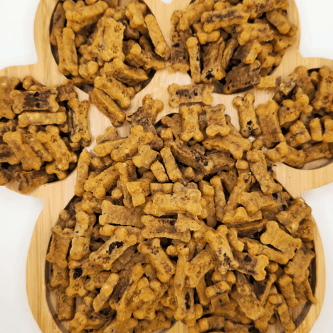 Display of Choco-Chip Pup Crunchers Dog Treats by Glamorous Pups, creatively arranged on a wooden serving board shaped like a paw. These treats are visually distinctive with their chunky, textured appearance and hints of carob chips, perfect for dog owners seeking a nutritious and tasty snack for their pets.