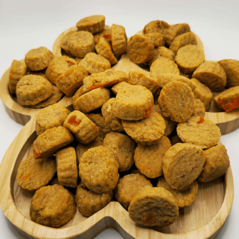 A wooden serving board arranged with Tropical Pupaya Paradise Dog Treats by Glamorous Pups, showcasing a delightful assortment of round and bone-shaped treats infused with the exotic flavors of papaya and pineapple. These gourmet dog snacks are ideal for pet owners looking for unique, healthy treat options for their dogs.