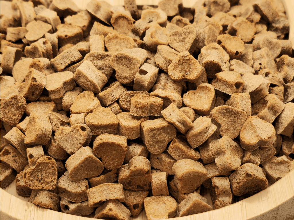 Close-up view of Chick 'N' Nip Love Bites Cat Treats by Glamorous Pups, showcasing the natural texture and heart-shaped form of these premium, all-natural cat treats on a cat-shaped wooden serving board.