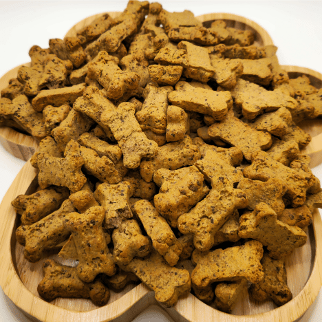 Assorted Pupkin Patch Snacks Dog Treats by Glamorous Pups, displayed on a wooden paw-shaped serving board. These bone-shaped treats are perfect for seasonal pampering, featuring pumpkin and cinnamon flavors tailored for doggy delight.