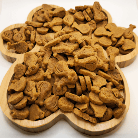 Assortment of Drumstick & Waffle Poppers Dog Treats by Glamorous Pups displayed on a wooden paw print-shaped serving board. These treats are crafted to resemble small drumsticks and waffles, showcasing their detailed shapes and enticing texture. Ideal for dog owners seeking nutritious and imaginative snack options, these treats highlight Glamorous Pups' commitment to high-quality, all-natural ingredients and made-in-the-USA production.